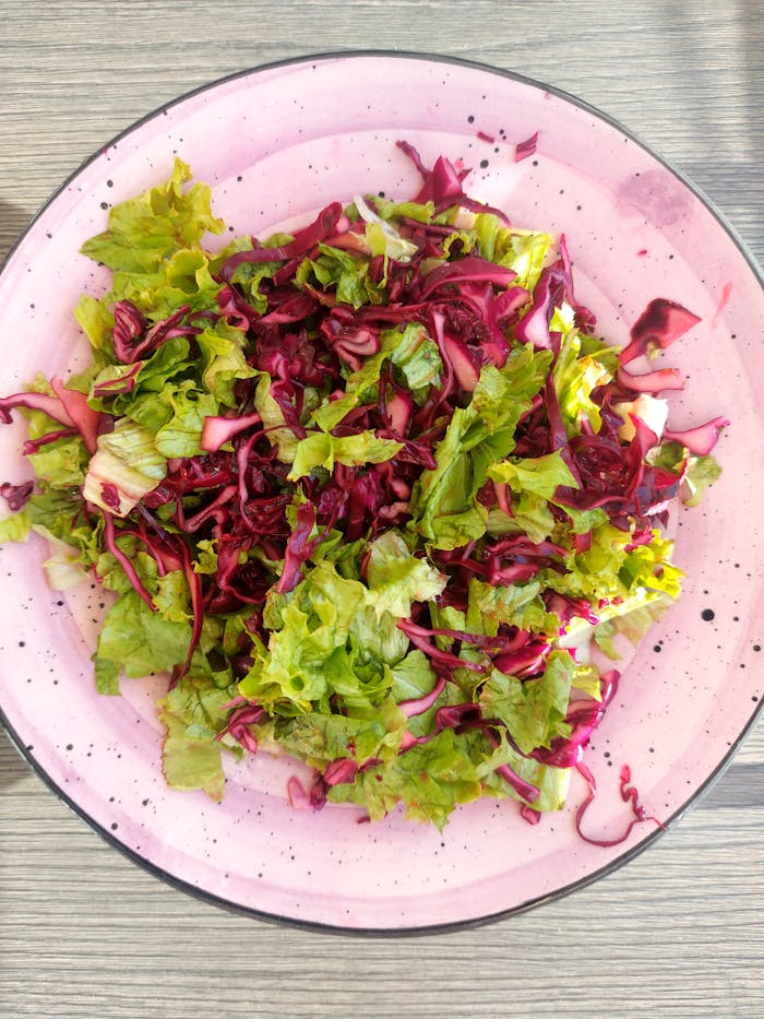 about-01 Healthy fresh mixed salad of greens and red cabbage on a pink plate.