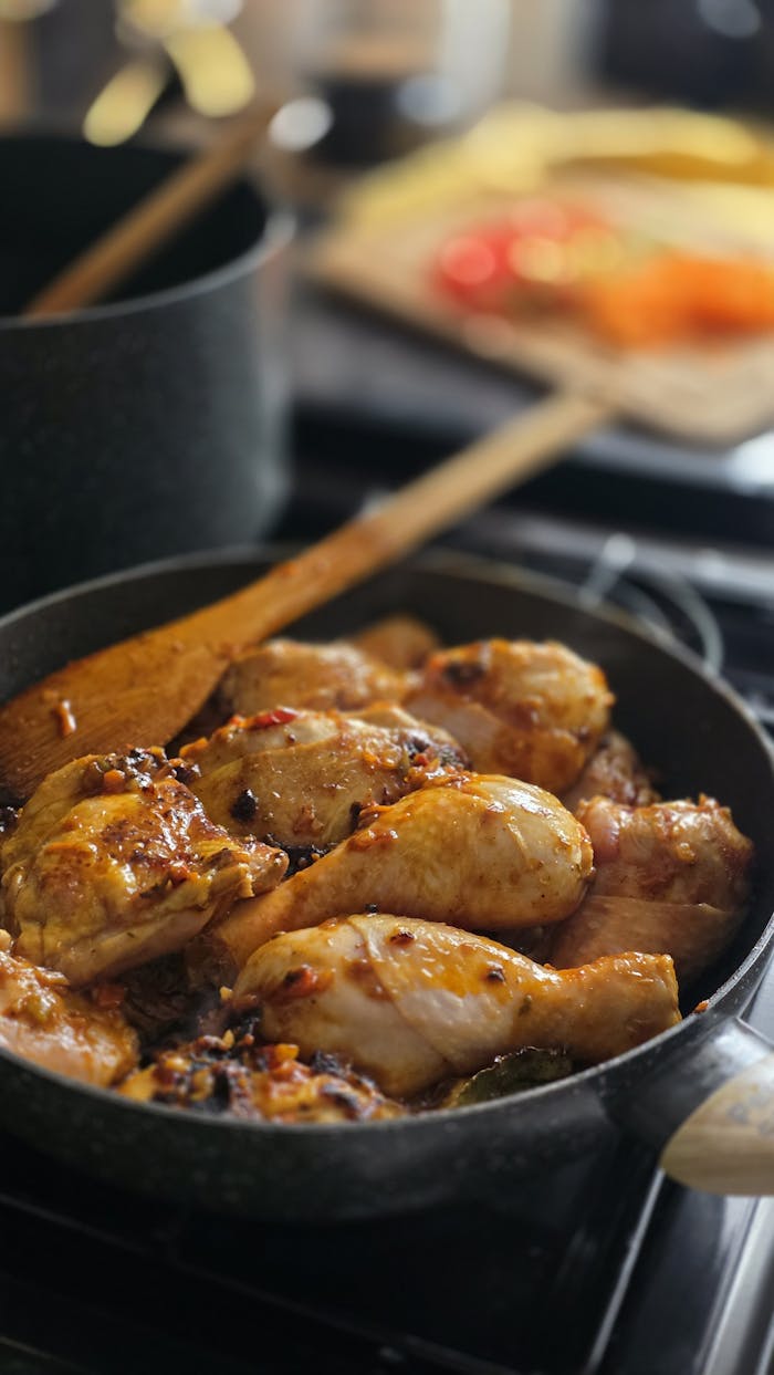 gallery-1 Close-up of seasoned chicken drumsticks sizzling in a pan, perfect for a home-cooked meal.
